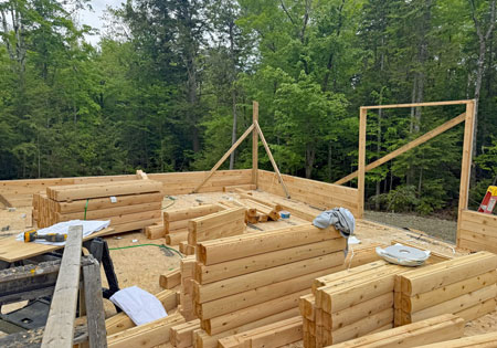 Partially built log home surrounded by trees