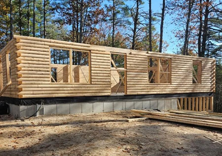 Partially built cedar log home in forest setting