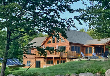 Large cedar log home with solar panels and trees
