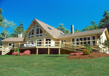Large cedar log home with A-frame design and wraparound deck.