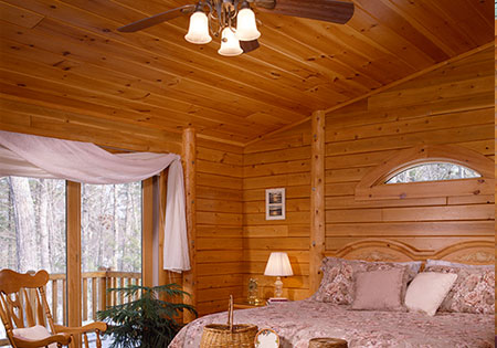Bedroom with cedar paneling, bed, and window view.