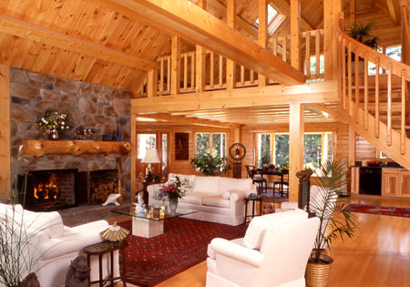 Spacious log home living room with stone fireplace and wooden beams