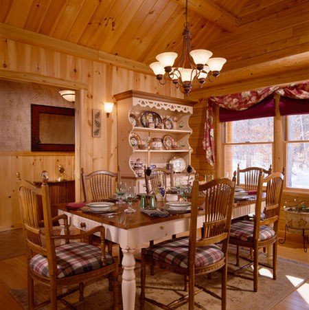 Dining room with wooden walls, table, chairs, and chandelier.