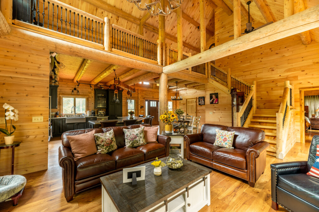Warm cedar log home living room with leather sofas and wooden beams.