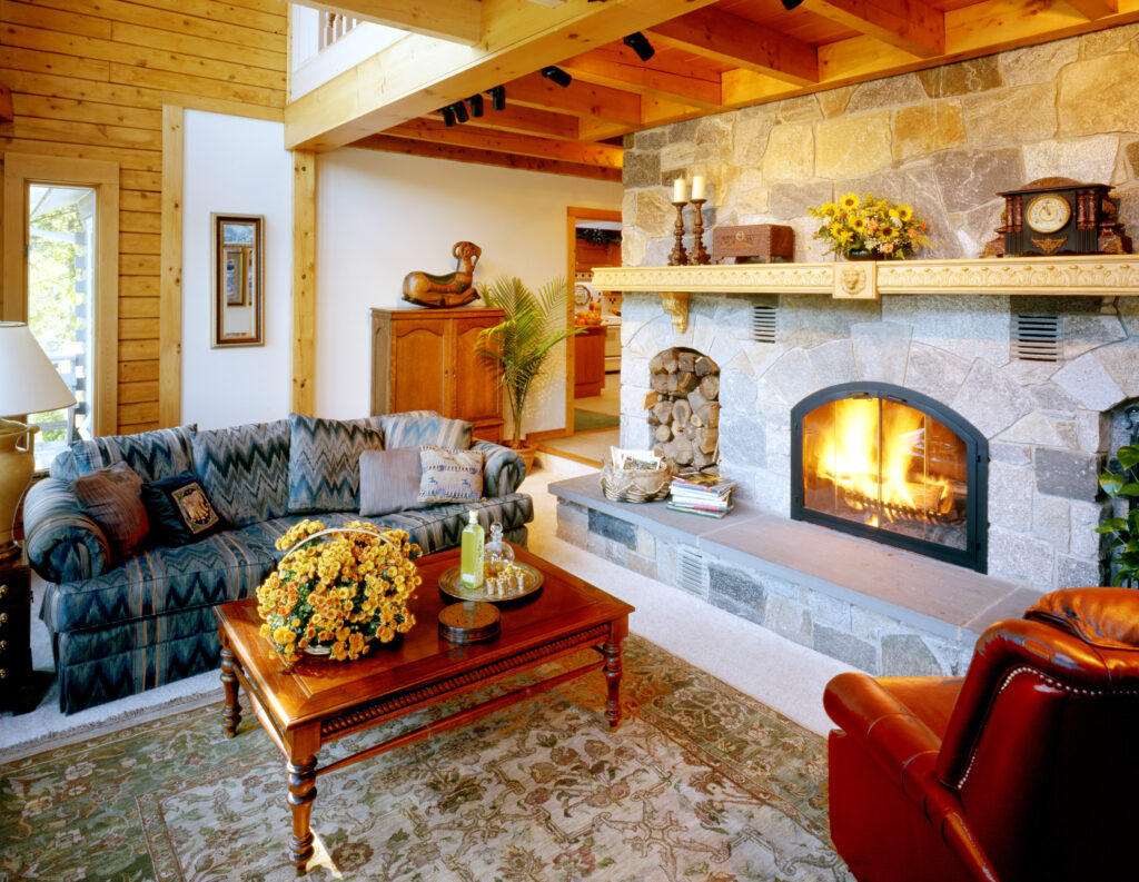 Living room with stone fireplace, wooden beams, and cozy seating.