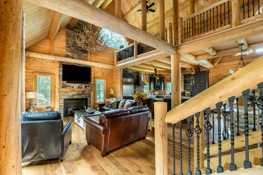 Open living area with log walls, leather sofas, and wooden beams.