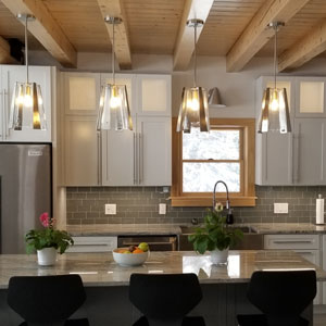 Contemporary kitchen with pendant lights, wooden beams, and plants.