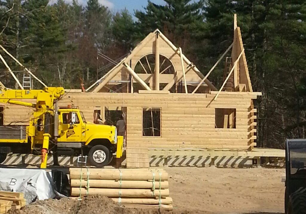 Partially built log home with construction equipment and logs